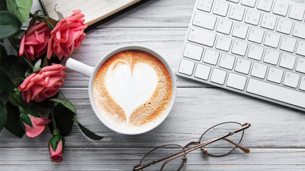 A cup of coffee with heart pattern on a desk