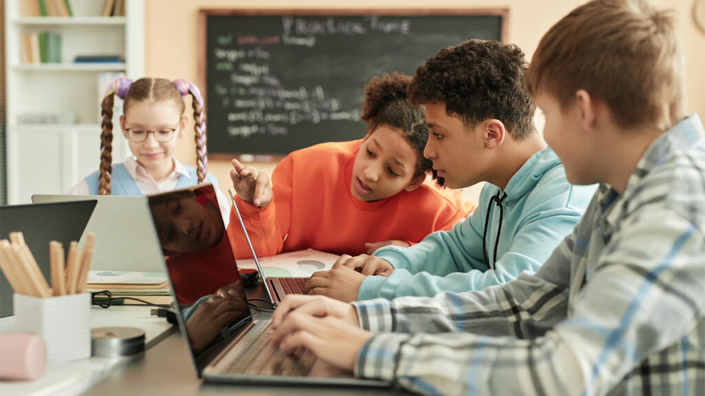 Group of children using laptops in school classroom together