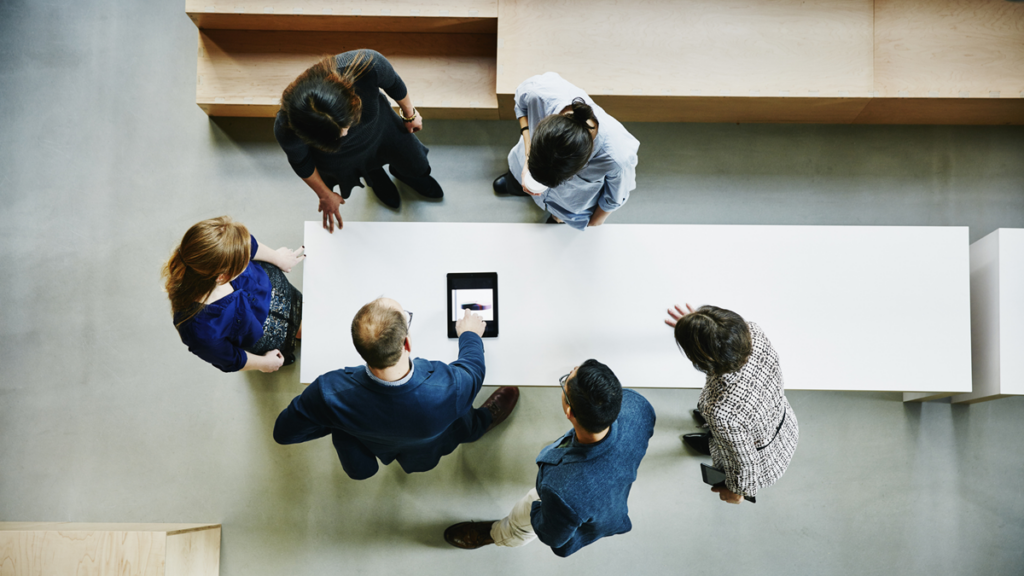 Business leaders stand around a table